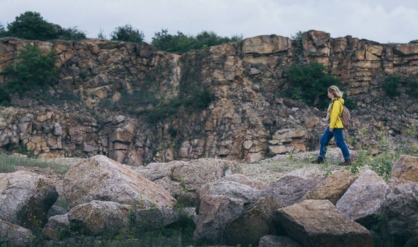 Жінка в жовтому плащі, що йде в гірському каньйоні
 - Фото, зображення