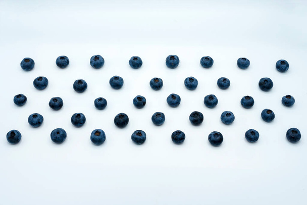 filas paralelas de arándanos jugosos maduros sobre un fondo blanco - Foto, Imagen