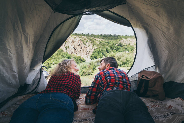 Young couple camping in a tent in the mountains overlooking rocky canyon. - Photo, Image
