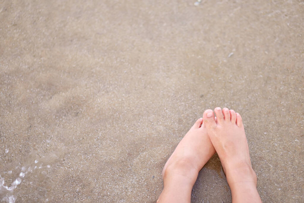 Ayak, ayak, çocuk ya da çocuk kumsalda oturup deniz suyu dalgalarıyla baş başa oturmak ve yaz tatilinde oyun oynamak için rahatlamak ve ailesiyle birlikte kopya alanı ve manzarası olan bir tatil yapmak. - Fotoğraf, Görsel