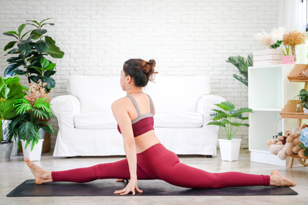 Frauen, die zu Hause im weißen Wohnzimmer Yoga praktizieren. Yoga- und Meditationskonzepte haben gesundheitliche Vorteile. Taubenpositionen - Foto, Bild