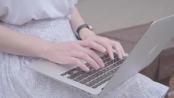 Une jeune fille utilise un ordinateur portable dans la rue. Toucher de près sur le clavier. - Séquence, vidéo