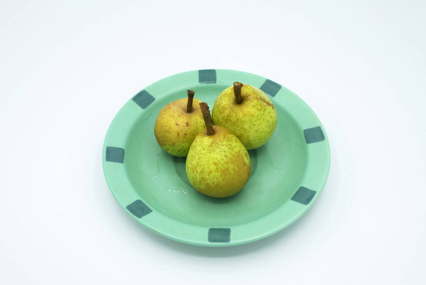 tres peras silvestres en un plato verde - Foto, Imagen