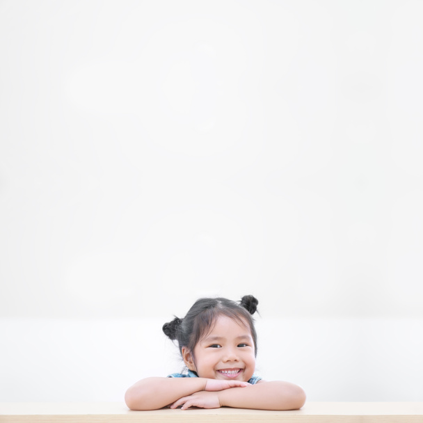 Aasialainen lapsi söpö tai lapsi tyttö ja opiskelija ajattelevat uutta ideaa ja onnellista hauskaa tai hymyileviä valkoisia hampaita puupöydälle päiväkodissa tai lastentarhassa ja lapset hammassairaalassa tai koulussa valkoisella. - Valokuva, kuva