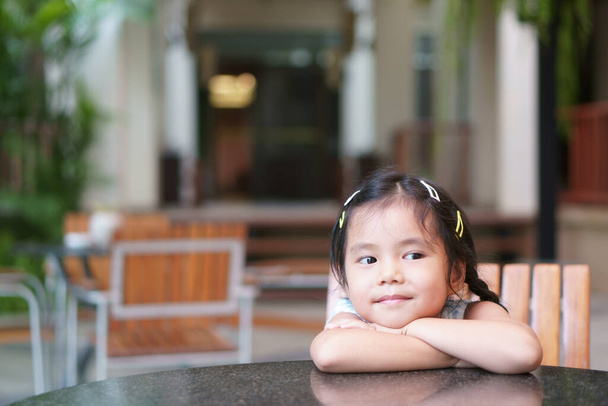Азиатский ребенок улыбается или ребенок девочка студент вакантной или думать о новой идее и счастливый весело или весело сидеть на столе и стуле в саду классе или детской дошкольного учреждения и отеля для отдыха отдыха отдыха - Фото, изображение