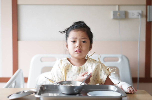Asian child patient or kid girl Influenza A sick and sad with cry to want encouragement with salt water in hand blood vessels on bed at hospital room for treatment healthcare with lunch food - Foto, Imagem