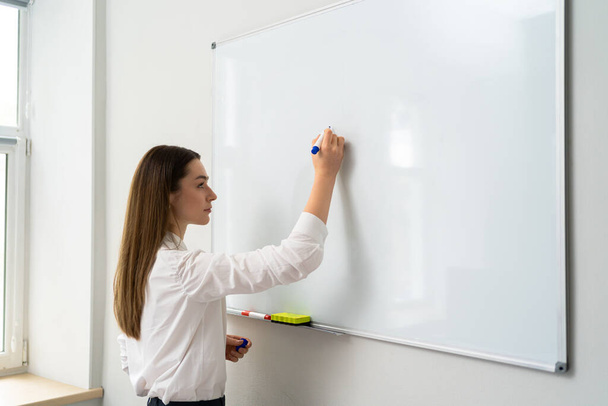 Junge Frau schreibt im Büro auf Whiteboard, - Foto, Bild