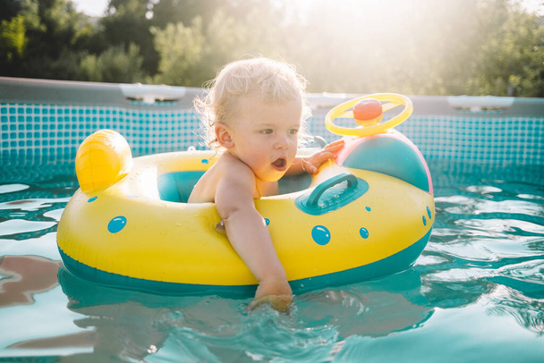 Happy baby boy bathing in inflatable ring. Swimming pool at summer - Foto, immagini