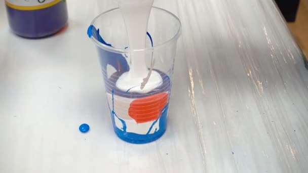Tiro de mezcla de pinturas acrílicas en taza de plástico - Metraje, vídeo