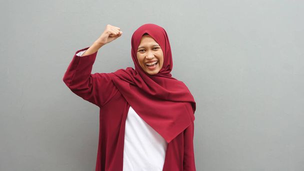Retrato de una joven musulmana asiática con los puños cerrados con hiyab  - Foto, imagen