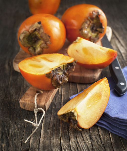 Fresh ripe persimmons on a wooden table - Valokuva, kuva