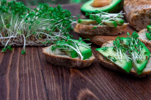 sandwiches with avocado and cressalata microgreen close-up on a wooden background. Healthy diet. filing option. vegetarianism. place for text. - Photo, Image