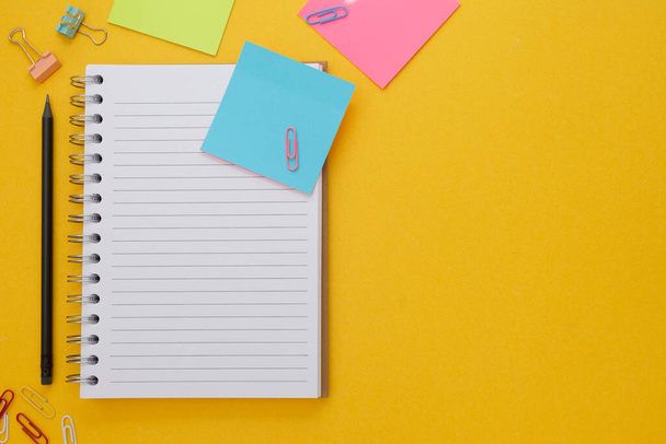 Back to school concept. Open empty notebook, school supplies, sticky notes. Yellow background. Flat lay - Foto, Bild
