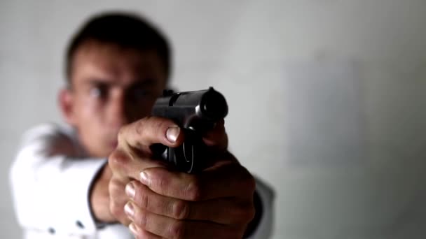 Молодой человек поднимает руки с пистолетом и прицеливается, готовясь к стрельбе - Кадры, видео