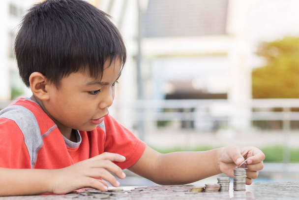 Portrait of happy Asian child boy counting the coins. Childhood put the money on the table. Kid saving money for the future concept. Children learning. - Fotografie, Obrázek