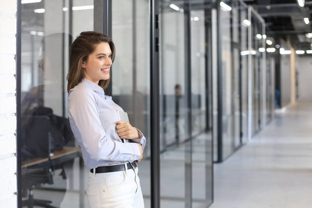 Businesswoman standing in the office corridor with digital tablet - Foto, afbeelding