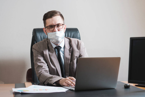 Retrato de jovem empresário de óculos e máscara facial em seu escritório pessoal. Negócios durante a quarentena
. - Foto, Imagem