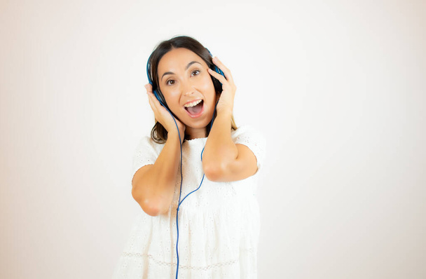 Gyönyörű nő fehér ruhában fülhallgatóval - Fotó, kép