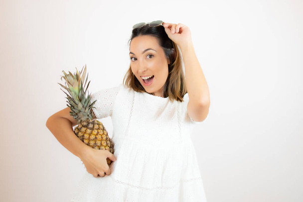 mooie jonge vrouw het oppakken van een ananas - Foto, afbeelding
