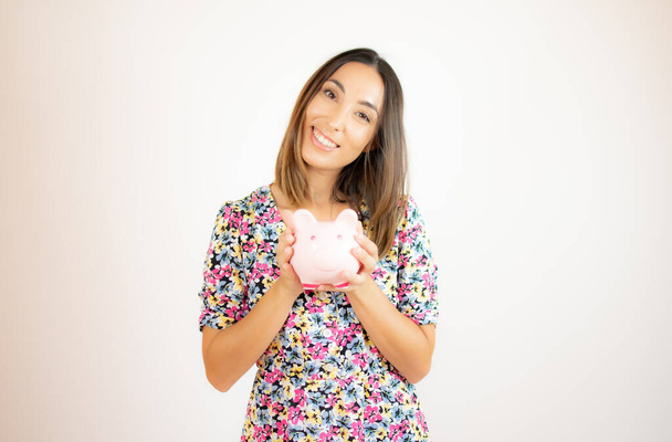 Pretty woman smiling with a piggy bank - 写真・画像