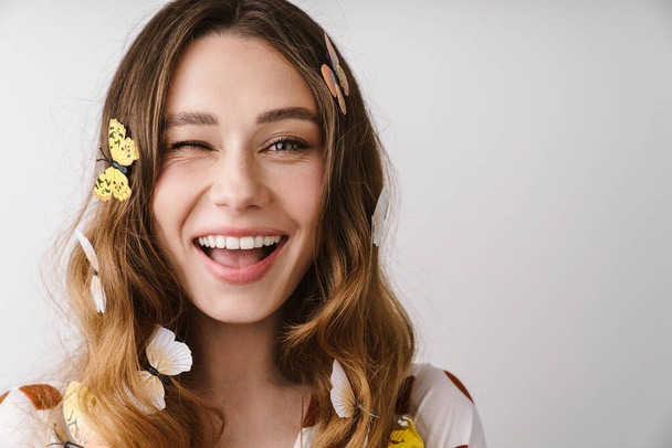 Photo of beautiful cheerful woman with fake butterflies laughing and winking isolated over white wall - Foto, imagen