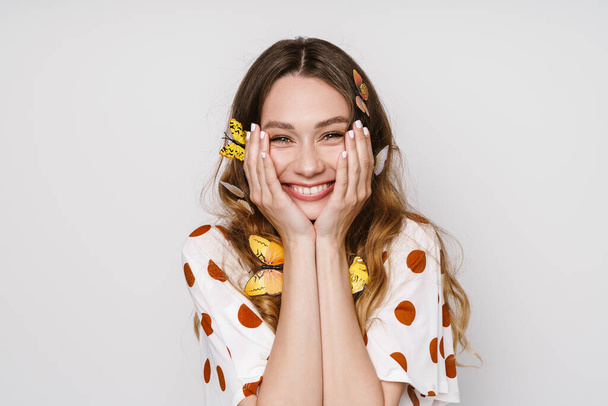 Photo of beautiful cheerful woman with fake butterflies smiling at camera isolated over white wall - Zdjęcie, obraz