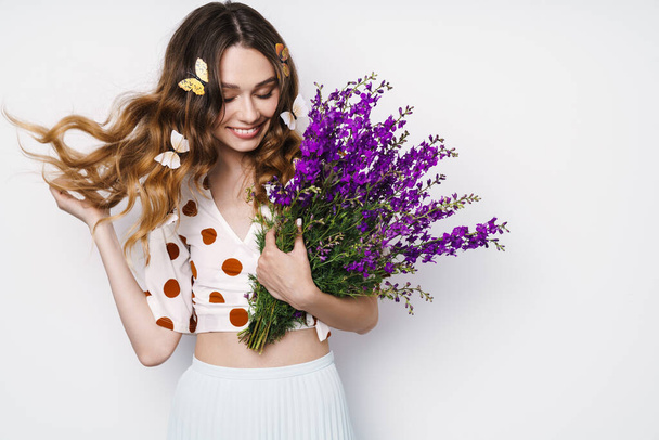 Photo of cheerful woman with fake butterflies and flowers posing and smiling isolated over white wall - Foto, Imagen
