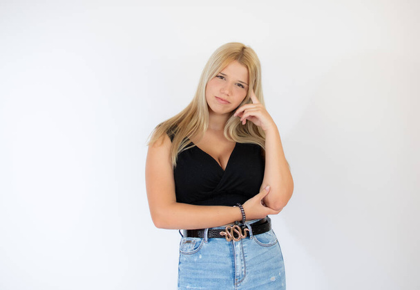 Beautiful blonde girl in black shirt with thoughtful gesture - Фото, изображение
