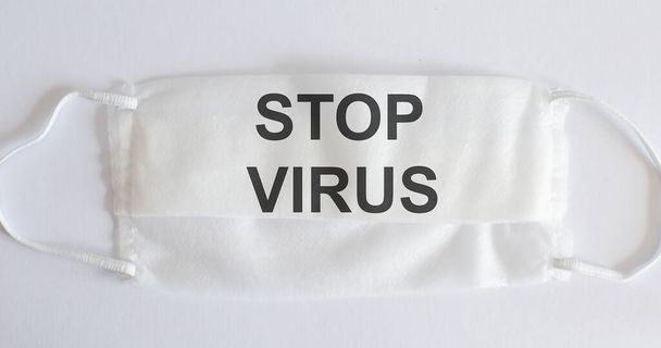 Máscara médica em um fundo branco com texto - PARAR VÍRUS. Conceito de proteção contra pandemia de vírus. Novel coronavirus - 2019-nCoV, conceito de vírus
. - Foto, Imagem