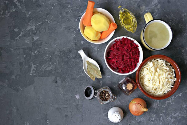 Ingredients for cooking borscht, traditional hot Russian soup with beetroot, cabbage and potatoes on a dark gray concrete background. - Фото, изображение