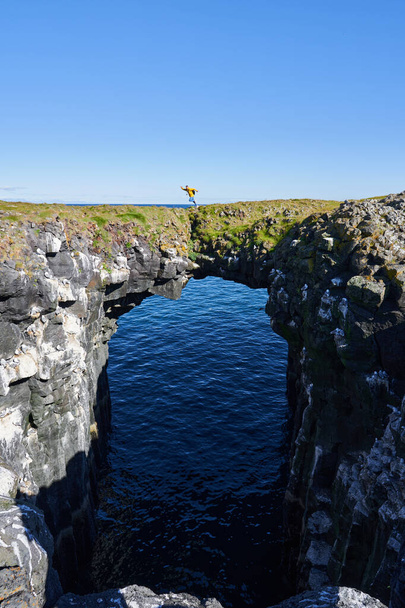 Hombre saltando desde el puente de piedra en Gatklettur en Islandia - Foto, Imagen