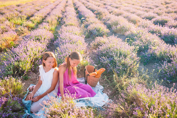Kids in lavender flowers field at sunset in white dress and hat - Foto, imagen