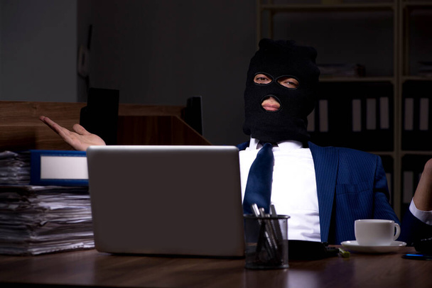 Hombre empleado robando información en la oficina durante la noche
 - Foto, imagen