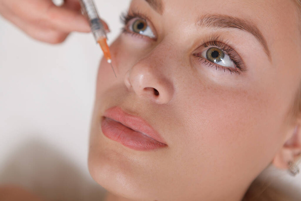 Close up top view shot of a beautiful woman getting face filler injections at cosmetology clinic - Foto, imagen