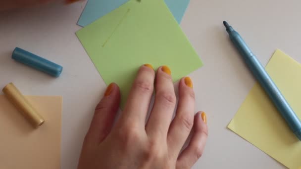 Write words, numbers and letters on square multi-colored note sheets - Séquence, vidéo