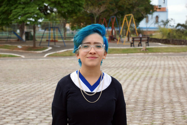 Porträt der schönen Teenager-Mädchen an einem schönen Tag in Brasilien mit glatten Haaren in blau im Freien auf dem Sportplatz gemalt - Foto, Bild