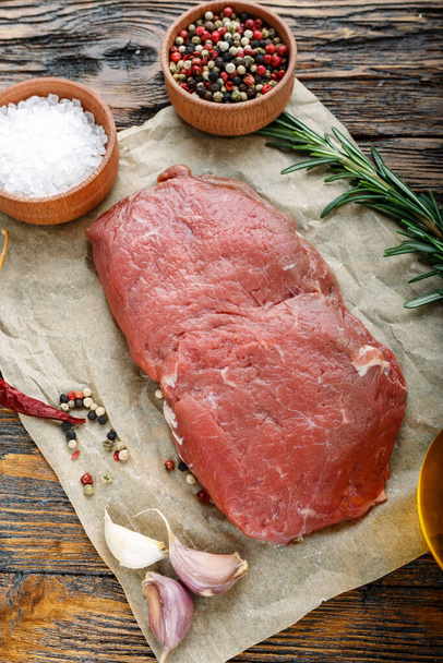 raw steak on a wooden background, on craft paper. meat for grilling or barbecue. place for tex - Foto, immagini