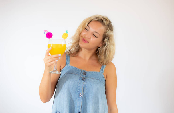 Bella donna bionda in abito blu sorridente con un cocktail di frutta - Foto, immagini