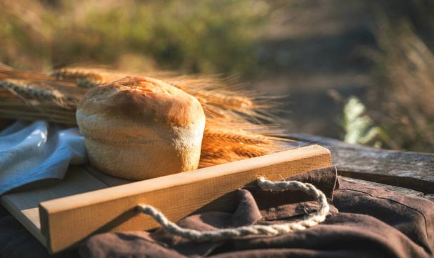 Pan y trigo en una caja de madera en condiciones naturales en la naturaleza - Foto, imagen