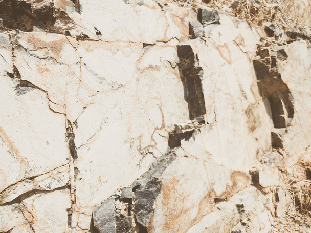 Natural background. Closeup edged shabby cliff cracks. Gray-brown stone rock texture of mountains. Vintage and faded matt style colour in tinted photo. Concept of geolog, mountaineering or hard work - Valokuva, kuva