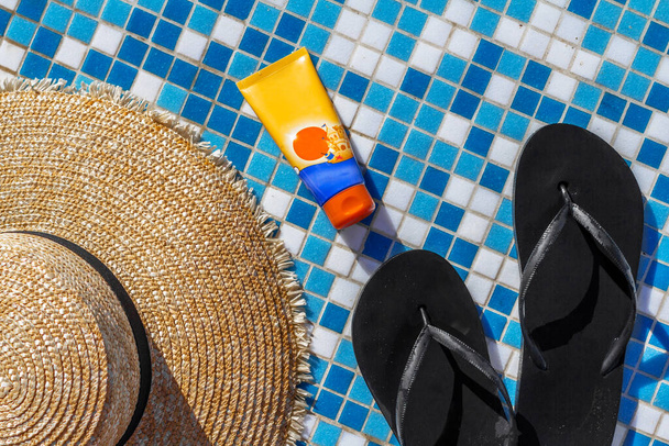 cappello di paglia in gomma infradito crema solare per il corpo e il viso a bordo piscina macro foto - Foto, immagini
