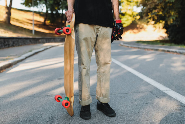 The guy is holding a board with red wheels. Skateboarding in the eternal city. - Photo, image
