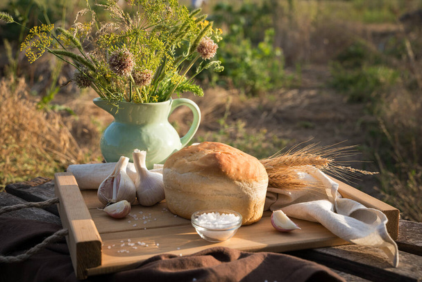 Ein Laib Brot und Weizen unter natürlichen Bedingungen in der Natur - Foto, Bild