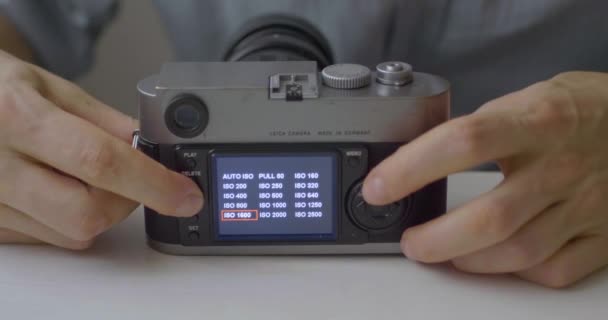 Uomo caucasico Visualizza le opzioni dalla vecchia fotocamera su un tavolo bianco  - Filmati, video