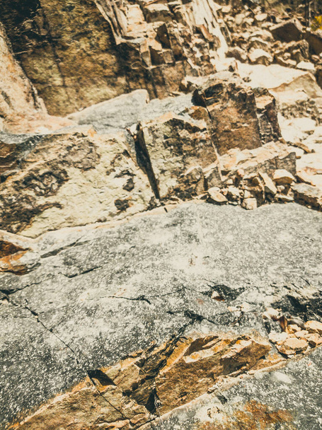 Natural background. Closeup edged shabby cliff cracks. Gray-brown stone rock texture of mountains. Vintage and faded matt style colour in tinted photo. Concept of geolog, mountaineering or hard work - Φωτογραφία, εικόνα