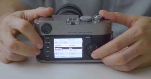 Kaukasier zeigt Optionen aus der alten Kamera auf weißem Tisch  - Filmmaterial, Video