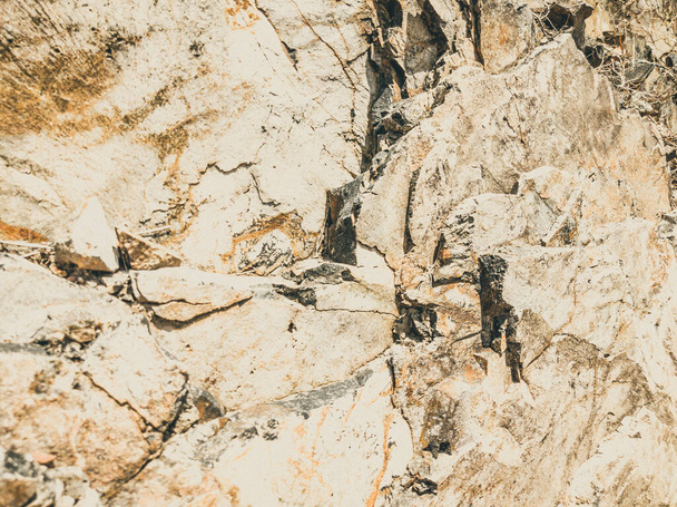 Natural background. Closeup edged shabby cliff cracks. Gray-brown stone rock texture of mountains. Vintage and faded matt style colour in tinted photo. Concept of geolog, mountaineering or hard work - Foto, afbeelding