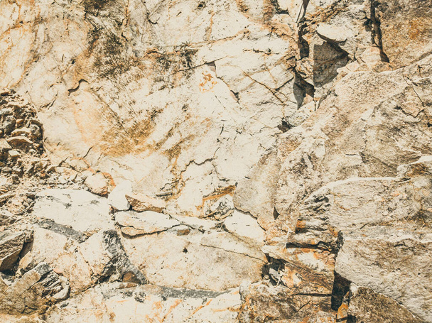 Natural background. Closeup edged shabby cliff cracks. Gray-brown stone rock texture of mountains. Vintage and faded matt style colour in tinted photo. Concept of geolog, mountaineering or hard work - Photo, Image