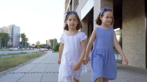 two cute little girls are walking along the city streets at sunset - Footage, Video