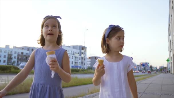 dos niñas lindas caminan por la ciudad y comen helado - Metraje, vídeo